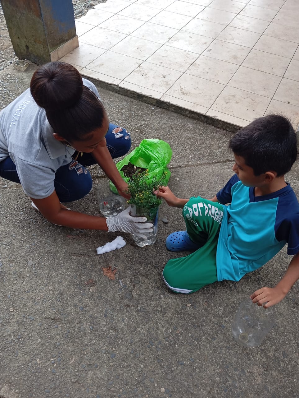 Estudiantes colocando semillas en botellas recicladas para reforestar