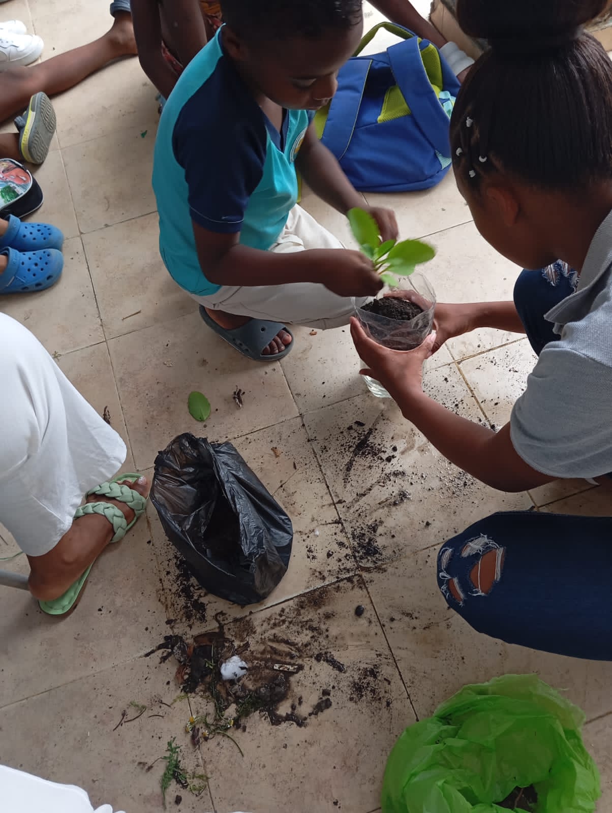 Grupo de niños trabajando juntos en proyecto de plantación de árboles en botellas